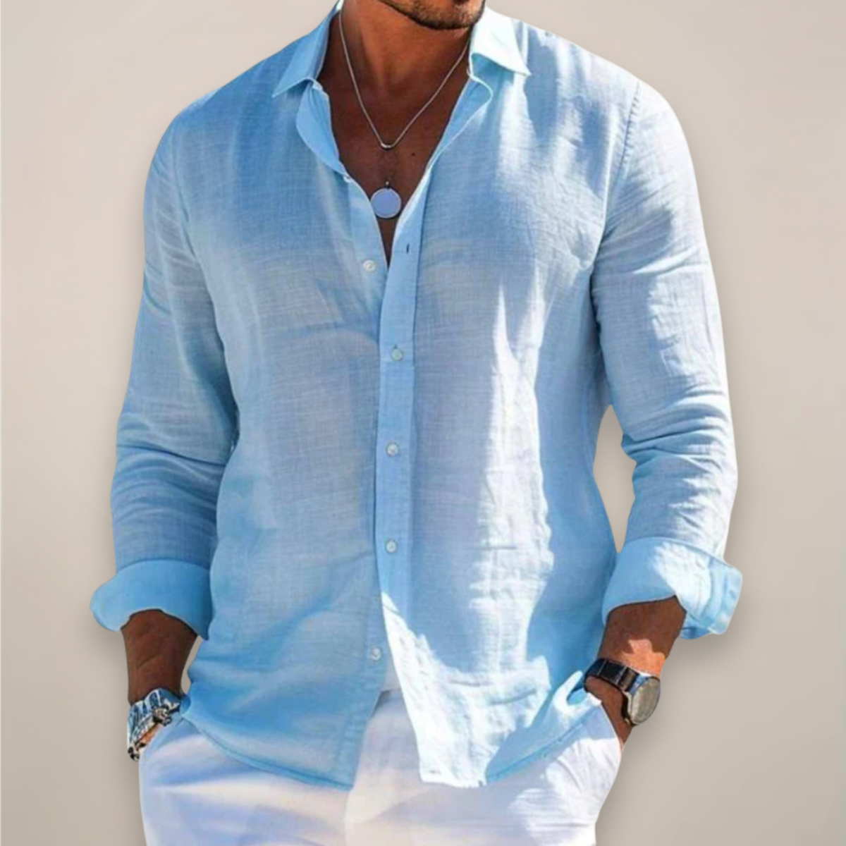 Model wearing the light blue version of the shirt, buttoned with sleeves rolled up, hands in pockets of white trousers. 3