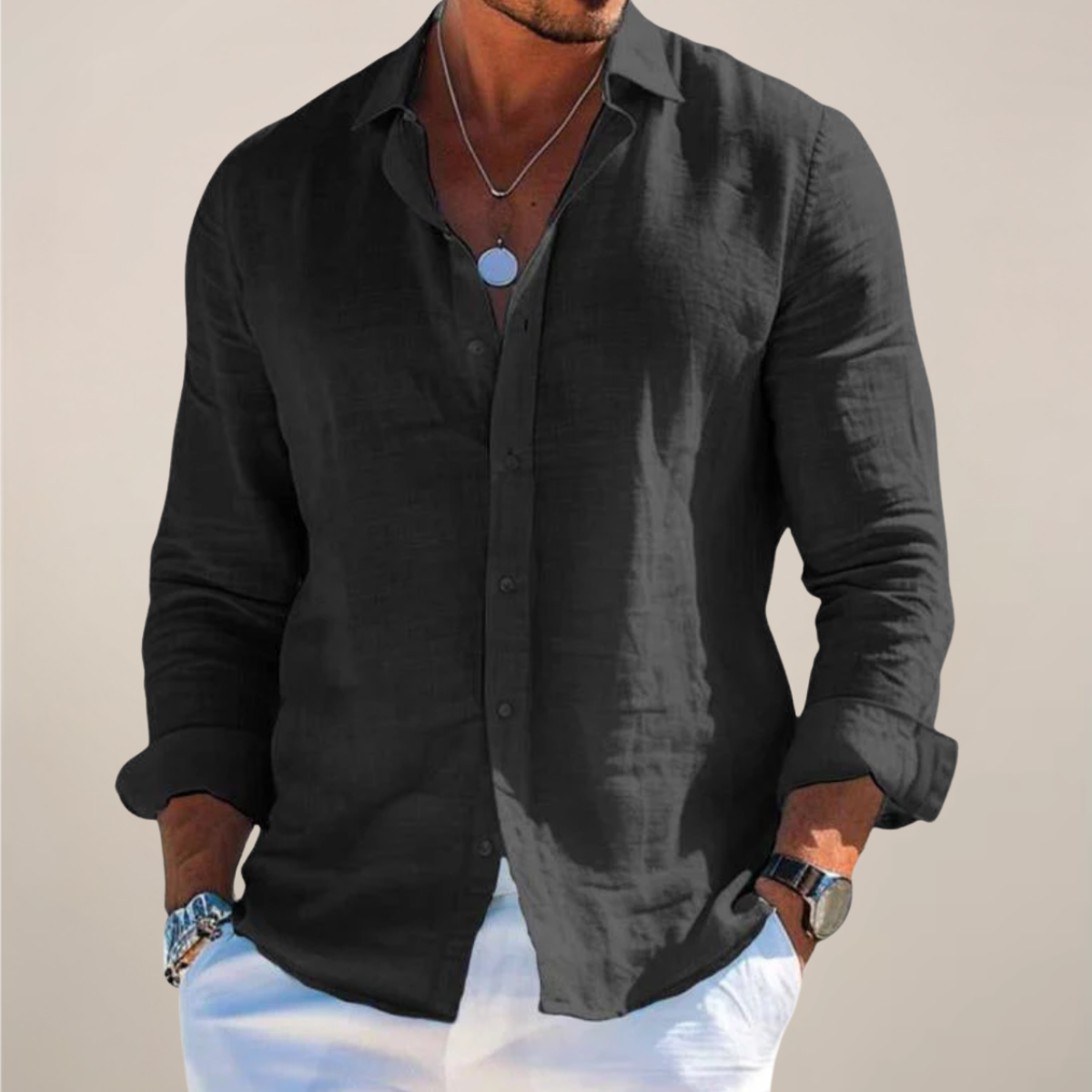 Model wearing the black version of the shirt, buttoned with sleeves rolled up, hands in pockets of white trousers. 4