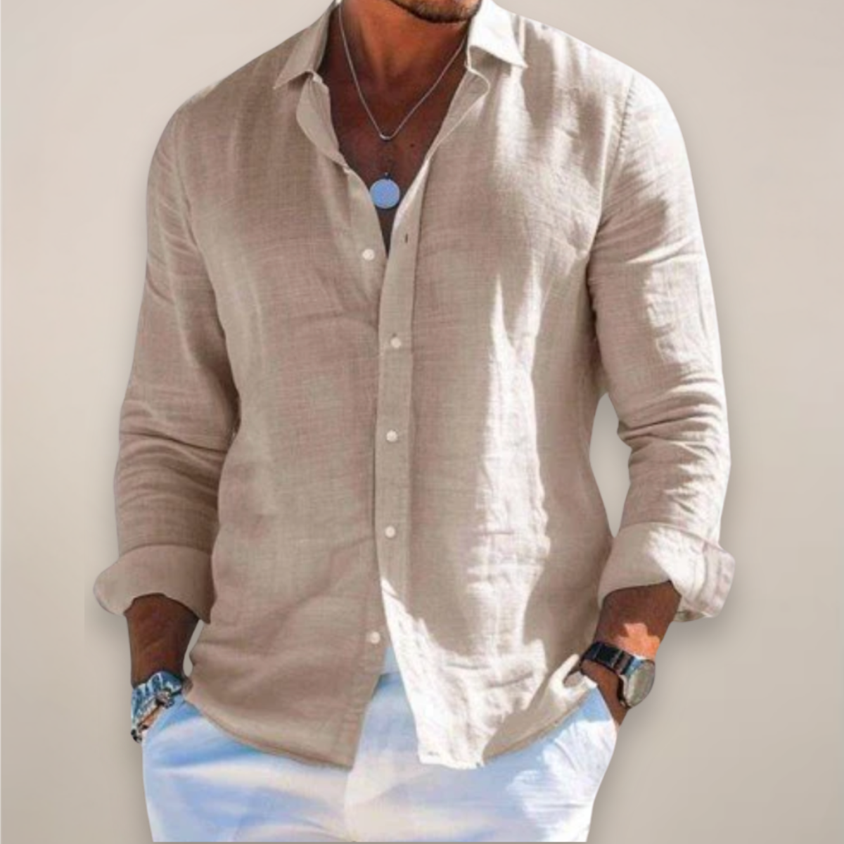 Model wearing the beige version of the shirt, buttoned with sleeves rolled up, hands in pockets of white trousers. 7