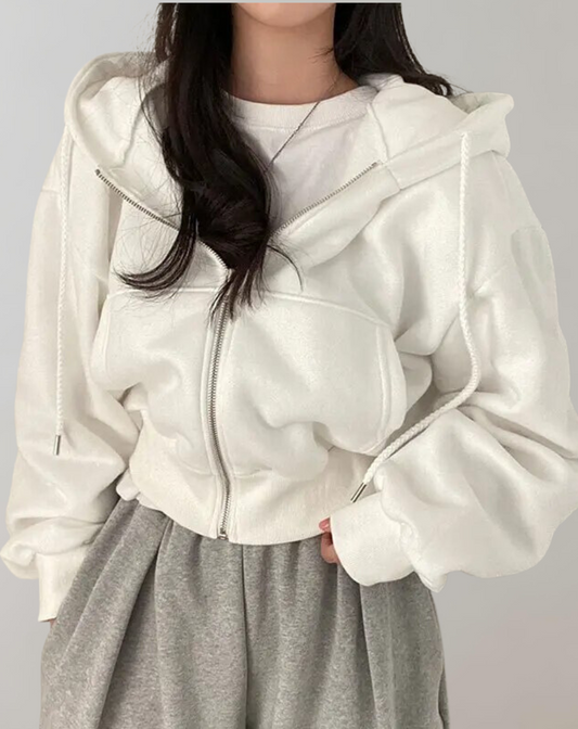 White cropped zip-up hoodie worn open over a white tee and grey sweatpants, with braided drawstrings hanging at the front. 1