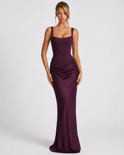 Front view of the dark plum satin dress on a model, with a seamed corset bodice, wide straps and a draped hip. 13