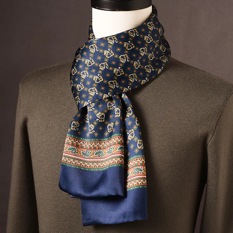 Navy silk scarf with a gold ornamental motif print, a green, orange and cream paisley border and plain navy ends, draped on a mannequin. 20