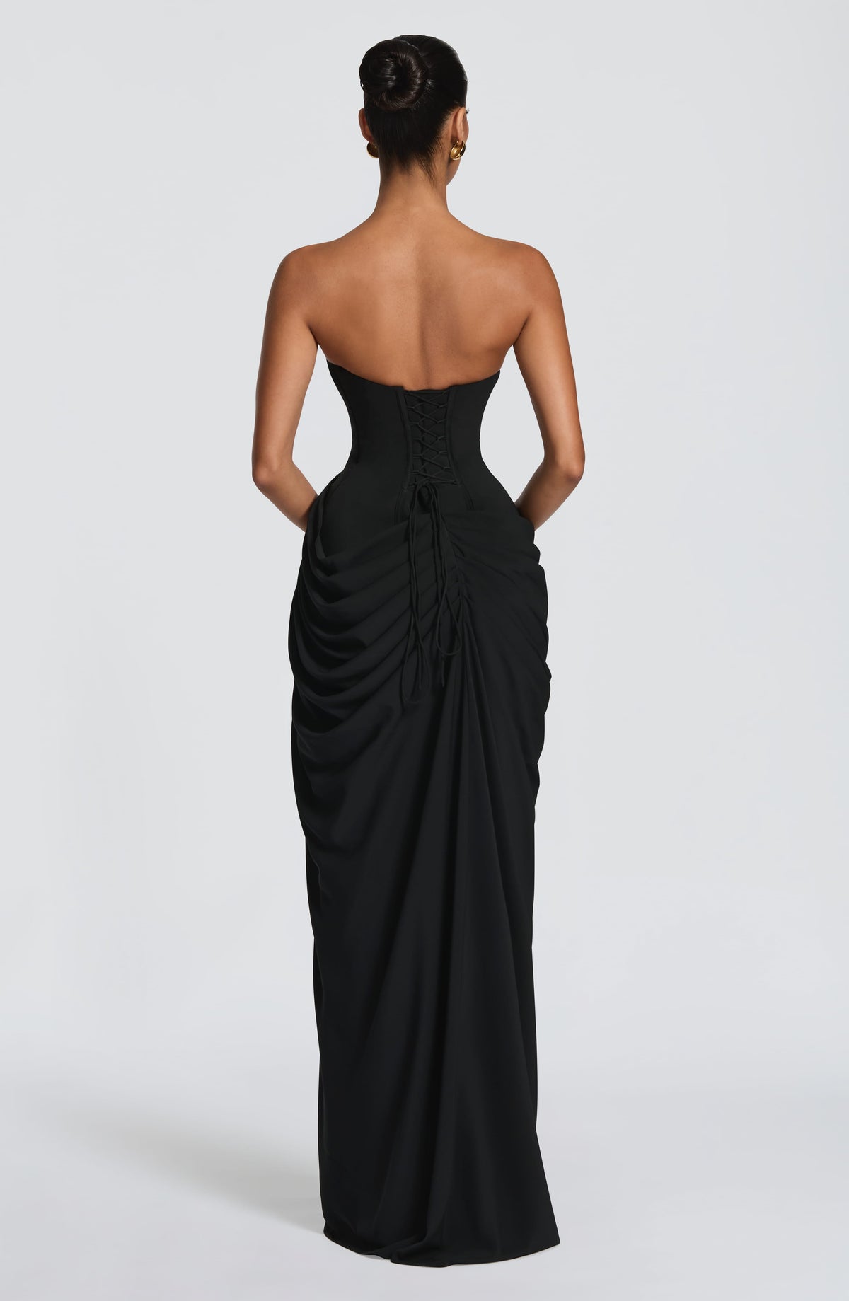 Back view of the black dress showing the lace-up corset back with long ties and the ruched skirt. 33