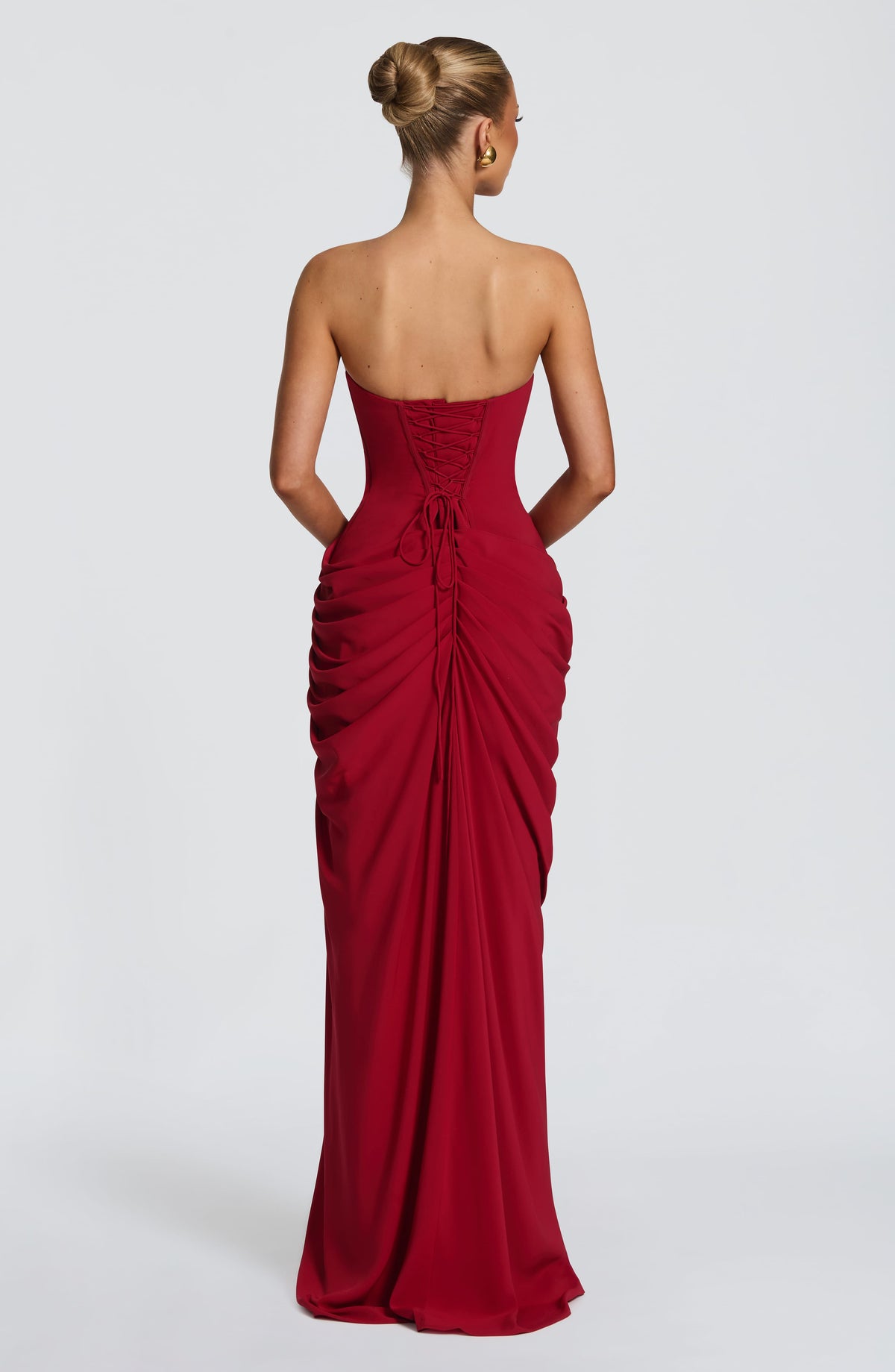 Back view of the red dress showing the lace-up corset back with trailing ties and gathered skirt. 28