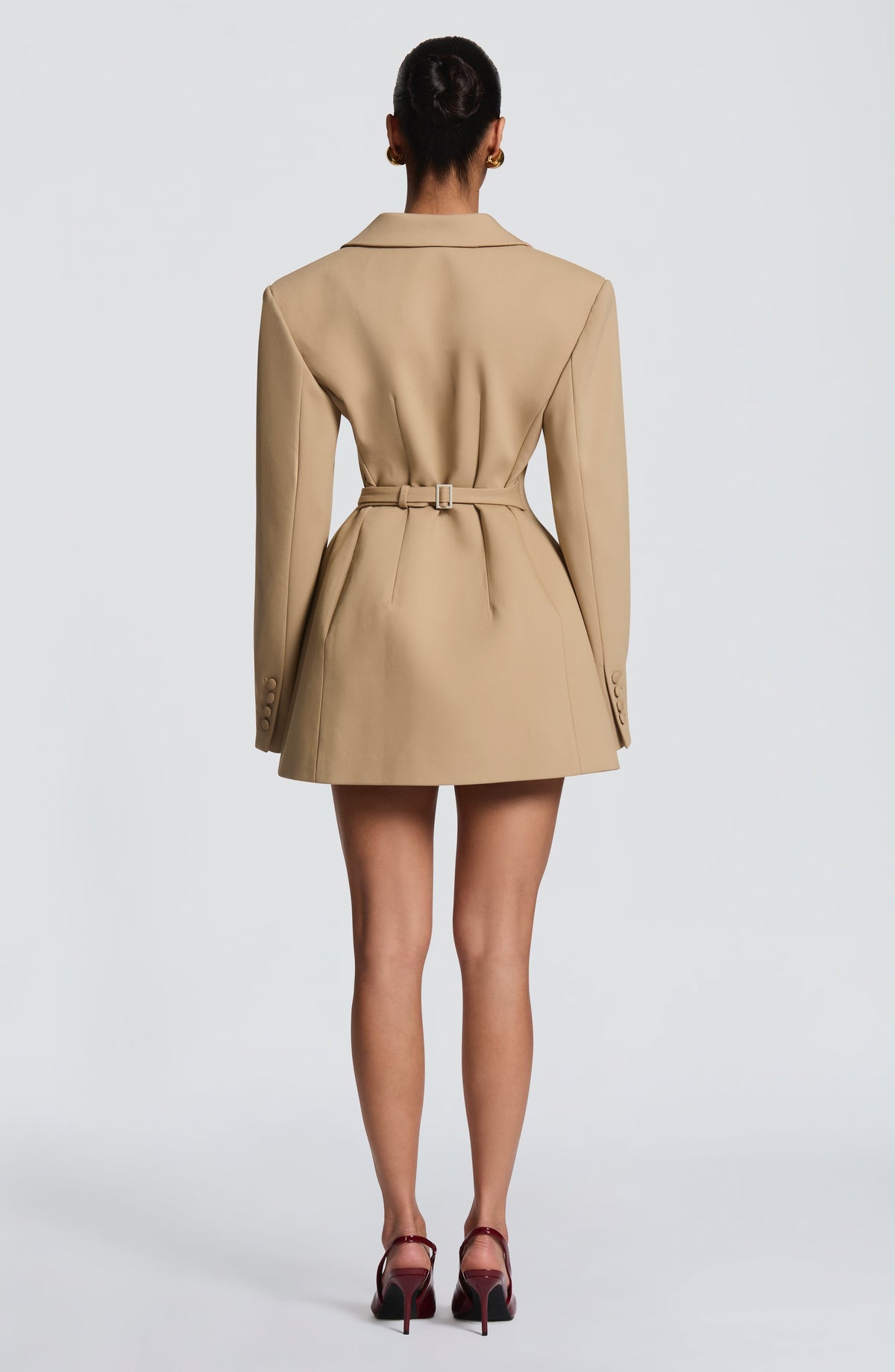 Back view of the camel blazer dress showing a fitted belt with a rectangular buckle, shaped seams and covered cuff buttons. 23
