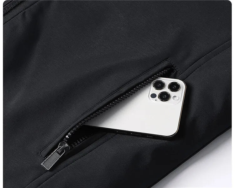 Close-up of the zipped side pocket on the black jacket with a white smartphone slipping inside. 7