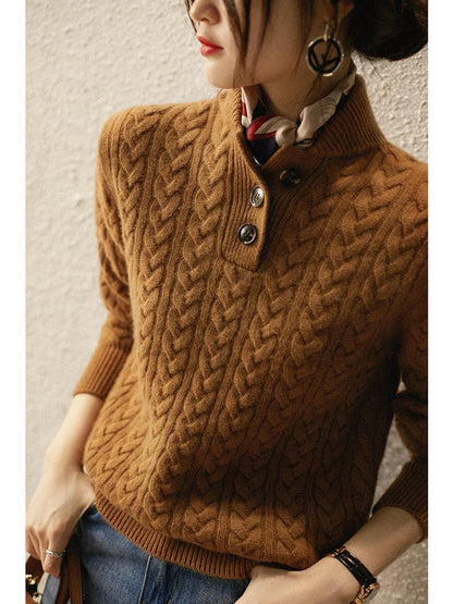 Model leaning against a textured wall in the brown cable-knit sweater, showing the button placket, scarf and large hoop earring. 4