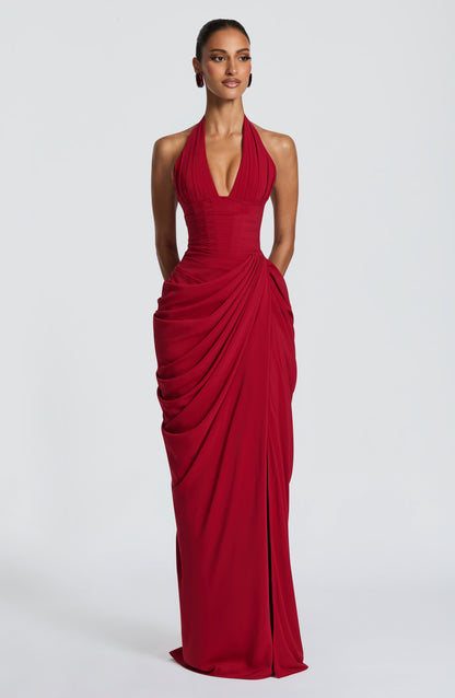 Model faces the camera in the red halterneck maxi dress, showing the pleated plunging bodice, corset waist and draped chiffon skirt. 21
