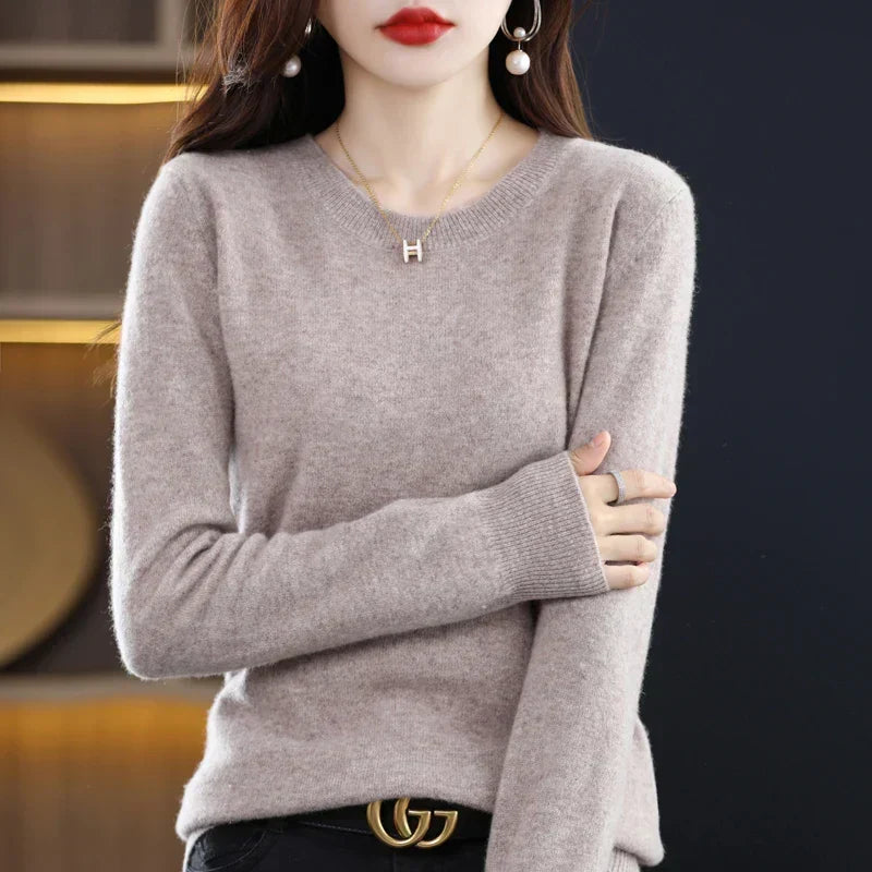 Model wearing the jumper in light greige with black trousers, arms crossed over her body 16