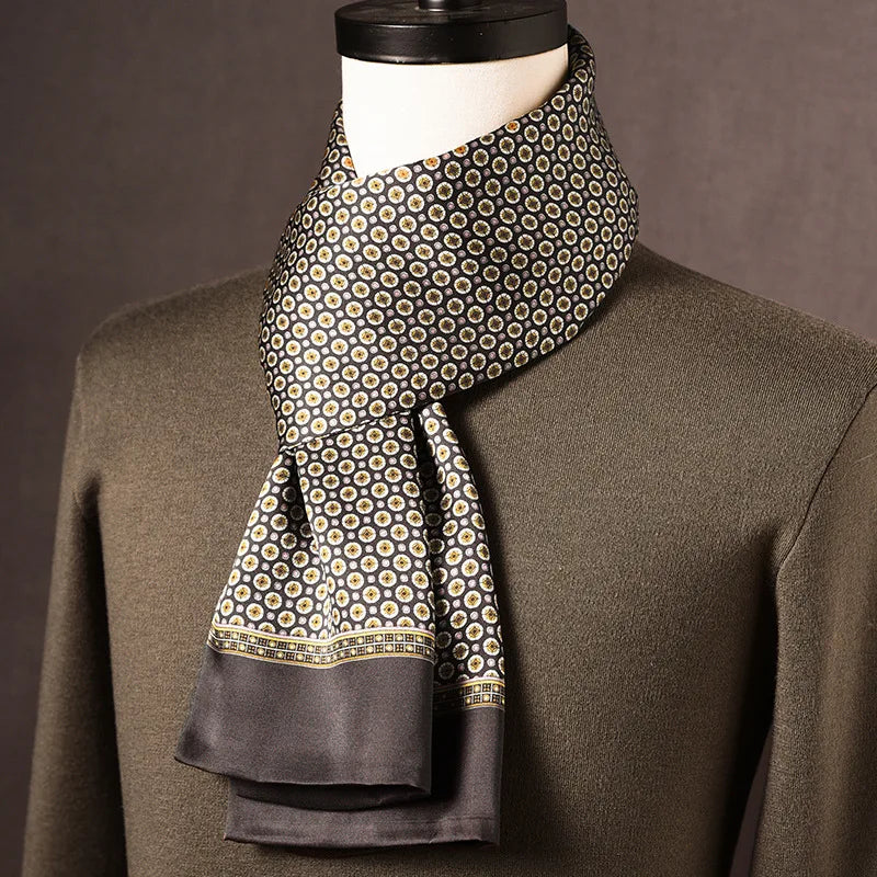 Dark silk scarf with a small cream and gold medallion print, a patterned border and plain grey ends, draped on a mannequin. 7