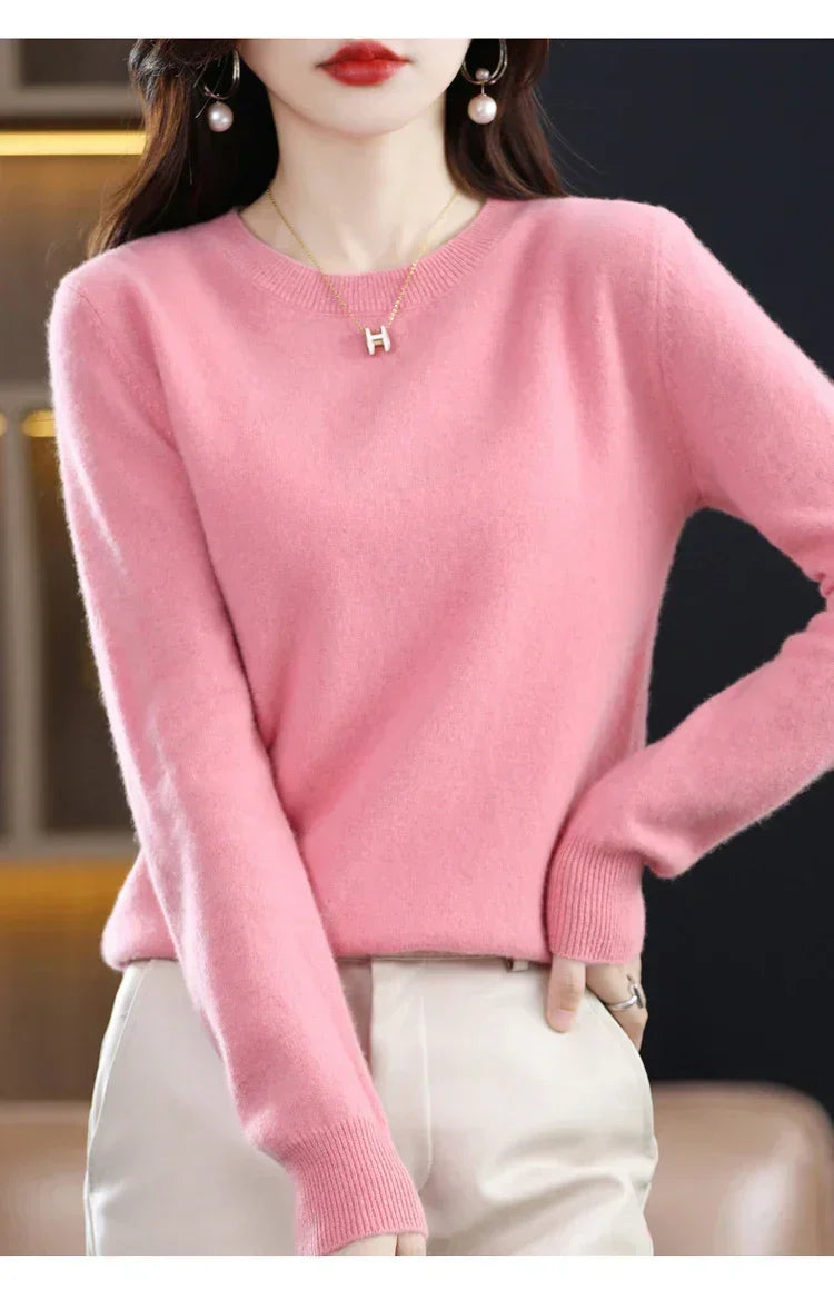 Model wearing the jumper in pink with cream trousers, one hand on her hip 8