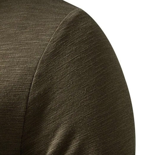 Close-up of the olive green henley's shoulder and sleeve seam, showing the flecked cotton texture 8