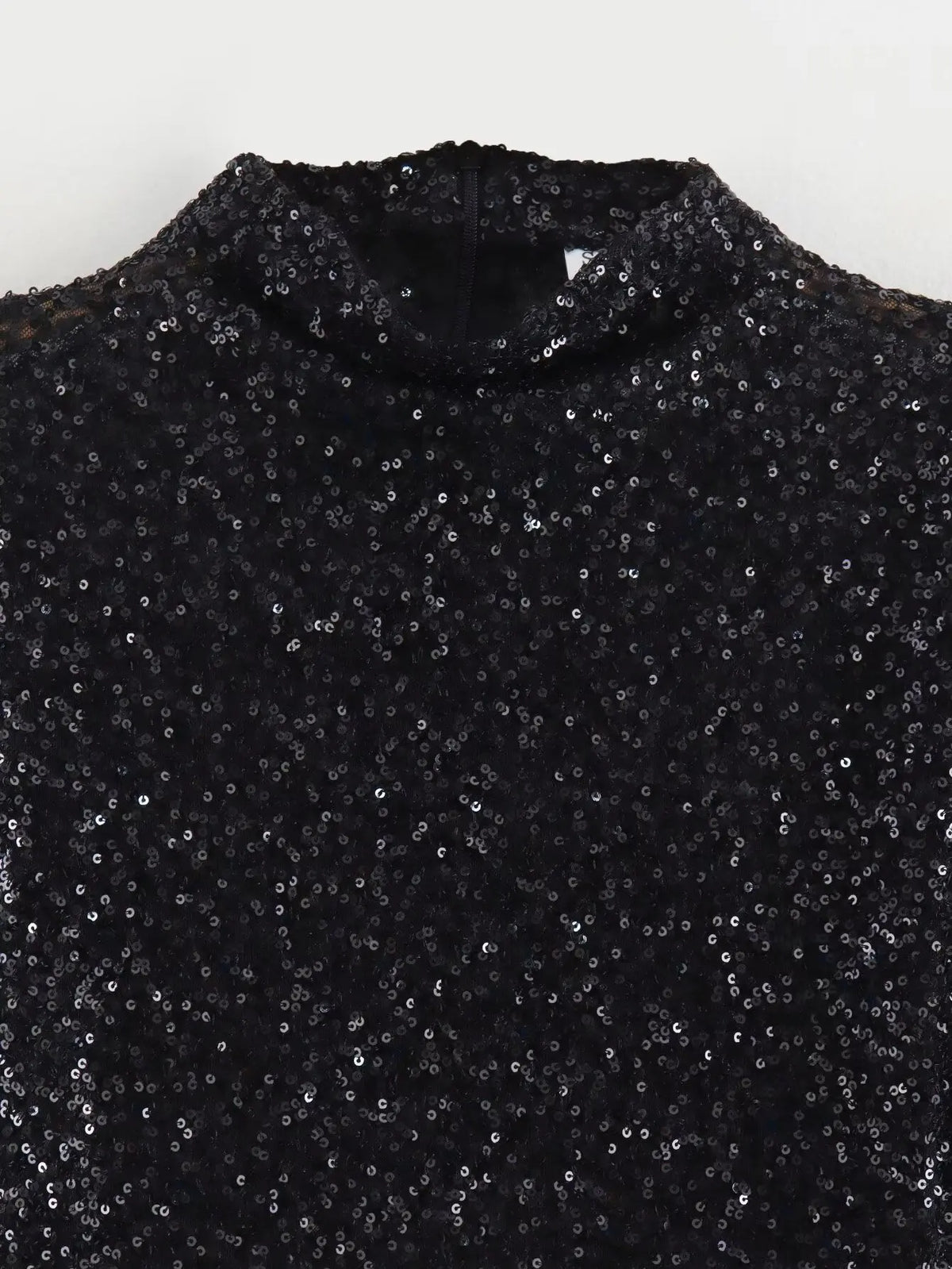 Close-up flat view of the black sequin fabric at the neckline and shoulders of the dress 4