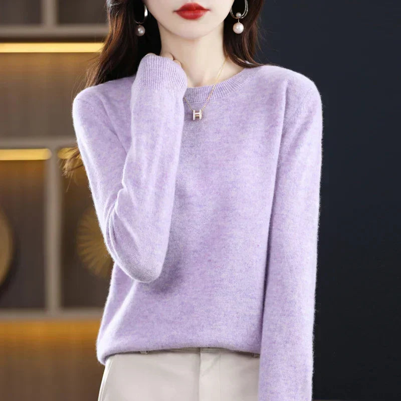 Model wearing the jumper in pale lilac with cream trousers, hand lightly touching her neck 17