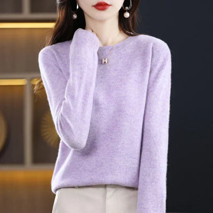 Model wearing the jumper in pale lilac with cream trousers, hand lightly touching her neck 17