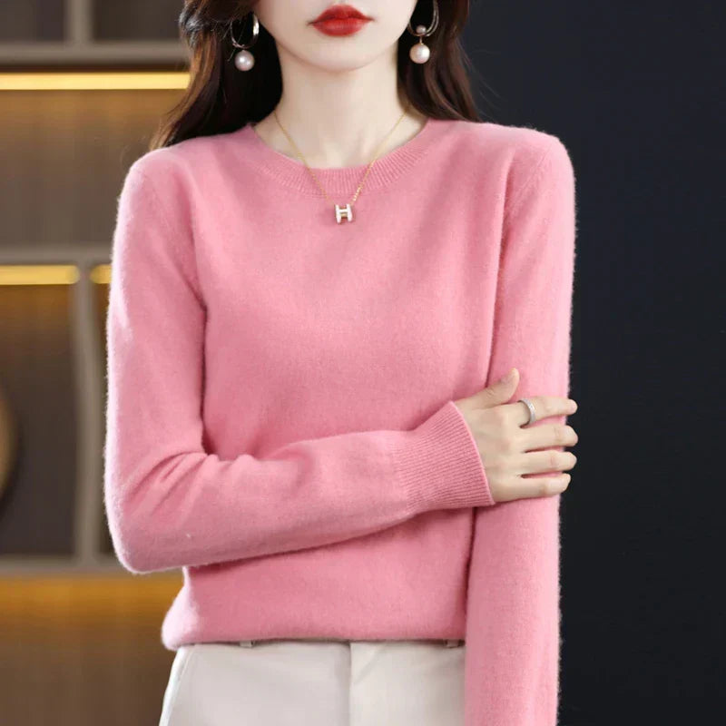 Model wearing the jumper in pink with cream trousers, arms folded across her body 10