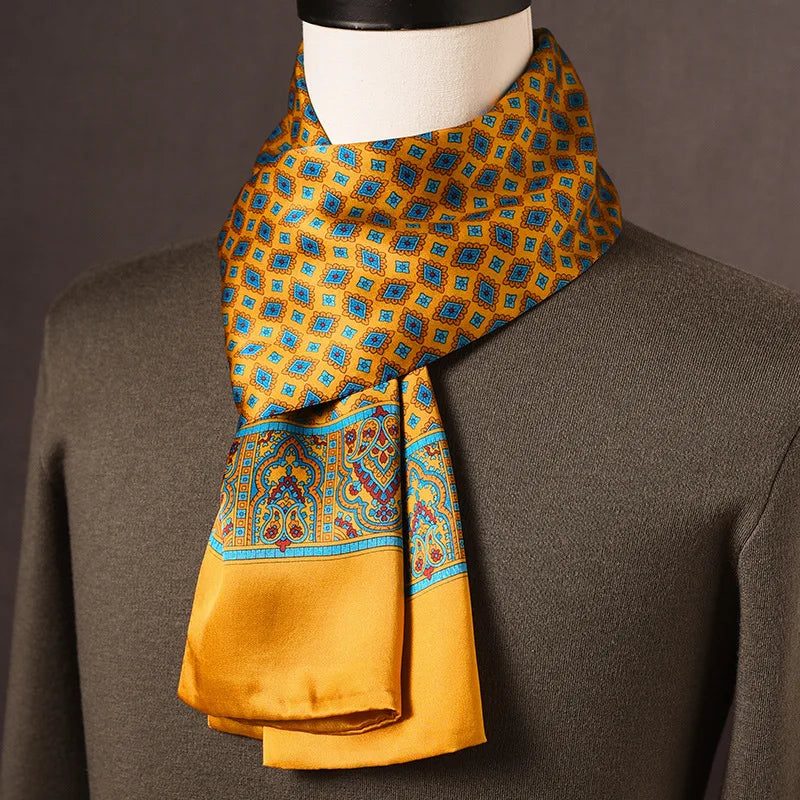 Golden-yellow silk scarf with blue diamond motifs, a paisley border and plain yellow ends, draped on a mannequin over an olive jumper. 5