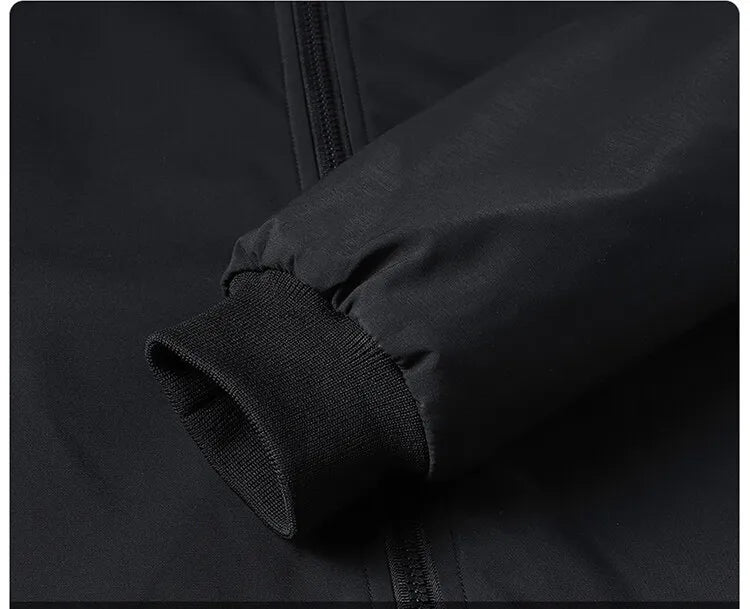 Close-up of the black jacket's ribbed knit cuff and gathered sleeve end beside the front zip. 8