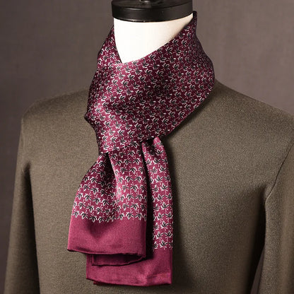 Burgundy silk scarf with a small white and dark floral print and plain burgundy ends, draped on a mannequin over an olive jumper. 17