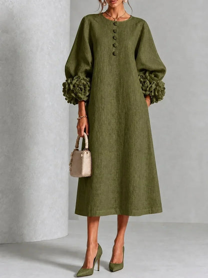 Front view of the olive green version on a model, with textured fabric, puffed sleeves, flower cuffs and flower buttons down the chest. 6