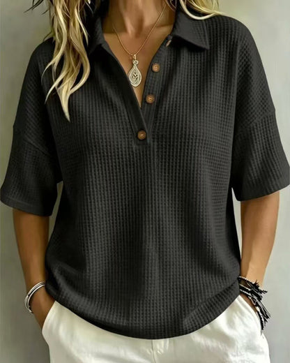 Black waffle knit polo top with three buttons, worn by a model with hands in pockets 5