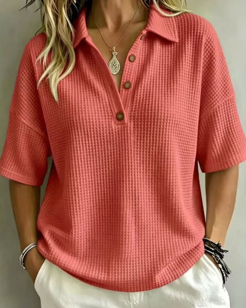 Coral-red waffle knit polo top with button placket, worn untucked with white trousers 4
