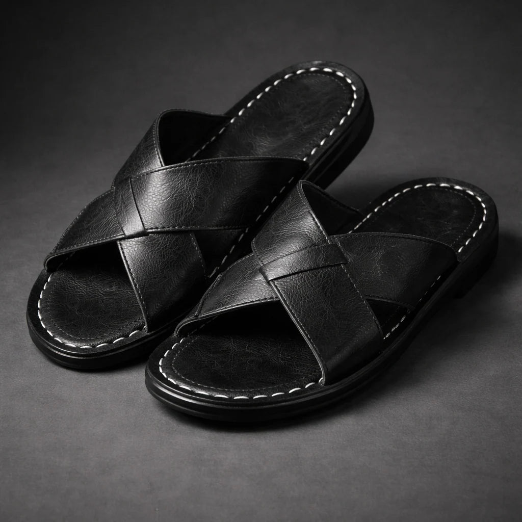Pair of black crossed-strap slip-on sandals with white contrast stitching round the footbed, shown at an angle on a grey backdrop. 2