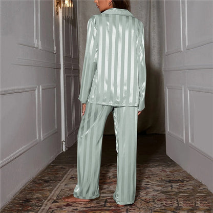 Back view of pale green striped satin pyjamas worn by a model standing in a hallway 13