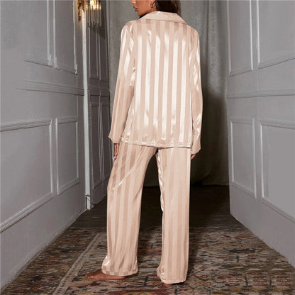 Back view of champagne striped satin pyjamas worn by a model standing in a hallway 2