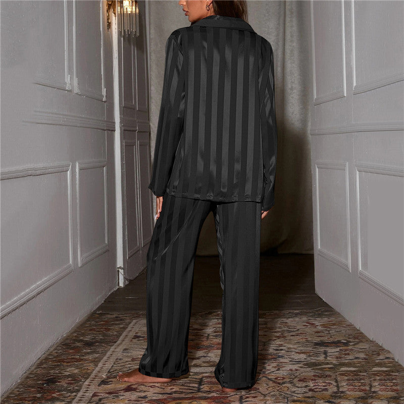 Back view of black striped satin pyjamas worn by a model standing in a hallway 5