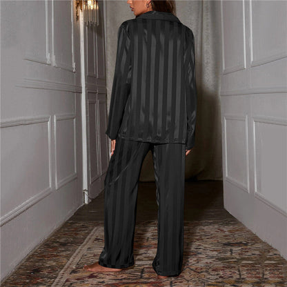 Back view of black striped satin pyjamas worn by a model standing in a hallway 5