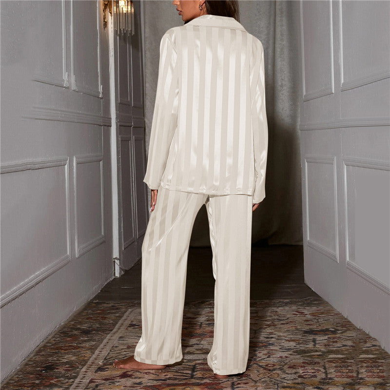 Back view of white striped satin pyjamas worn by a model standing in a hallway 8