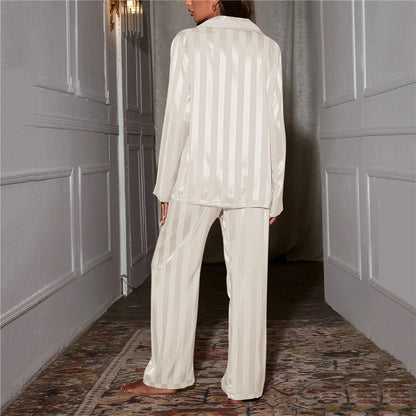 Back view of white striped satin pyjamas worn by a model standing in a hallway 8