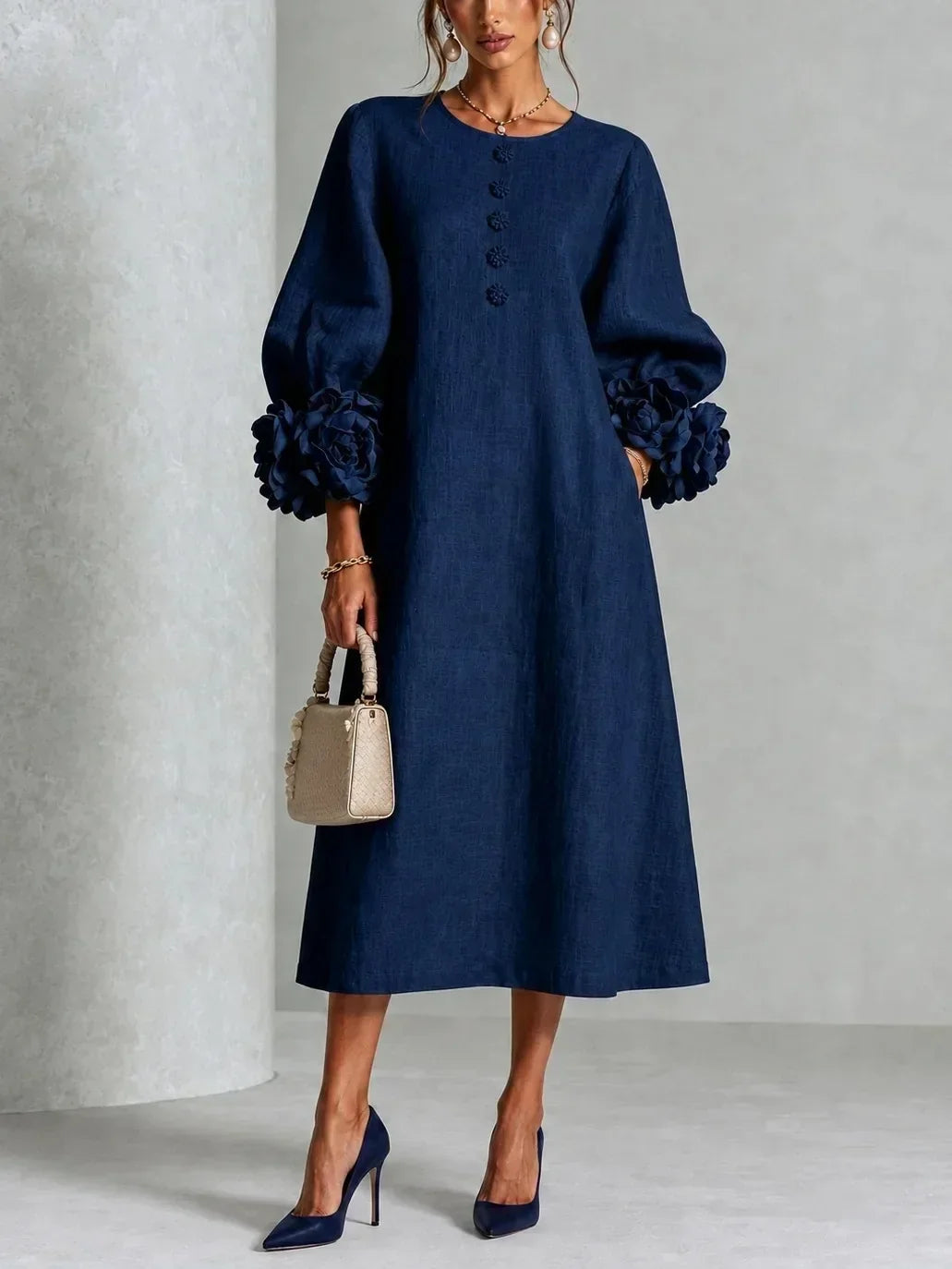 Front view of the navy version worn by a model, showing puffed sleeves with large flower cuffs and a row of flower buttons at the neckline. 2