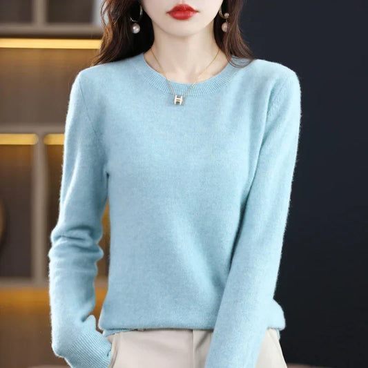 Model wearing the crew-neck jumper in pale sky blue with cream trousers and a pendant necklace 2
