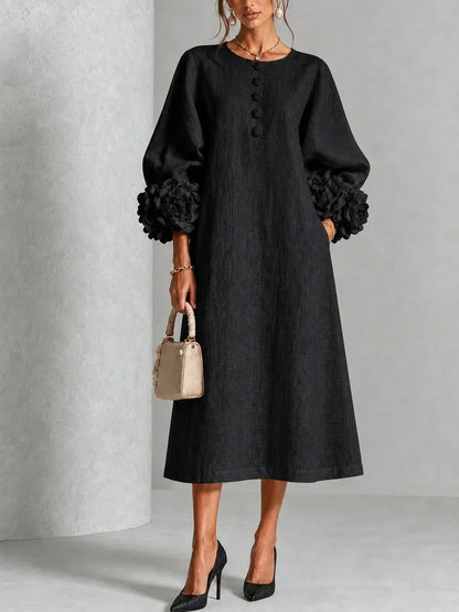 Model wears the black version, front view, showing the loose A-line shape, flower buttons at the neckline and oversized flower cuffs. 5