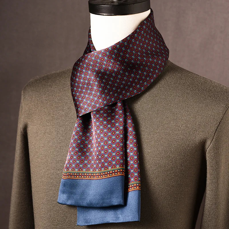 Silk scarf in burgundy and pale blue with a small medallion print and plain blue ends, draped on a mannequin over an olive jumper. 1