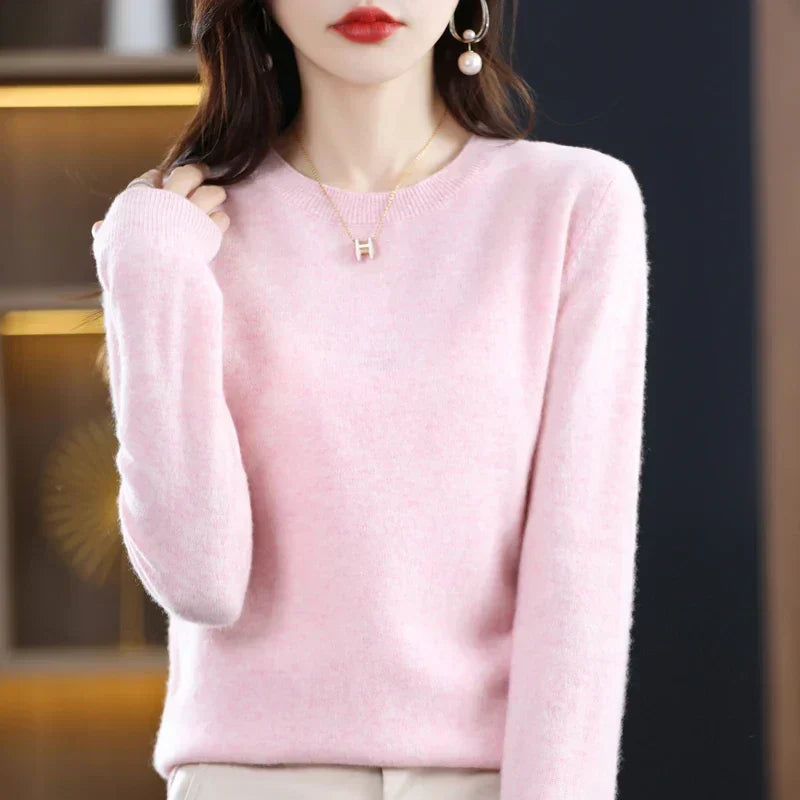 Model wearing the round-neck jumper in soft pink, one hand touching her hair, with pearl earrings 23