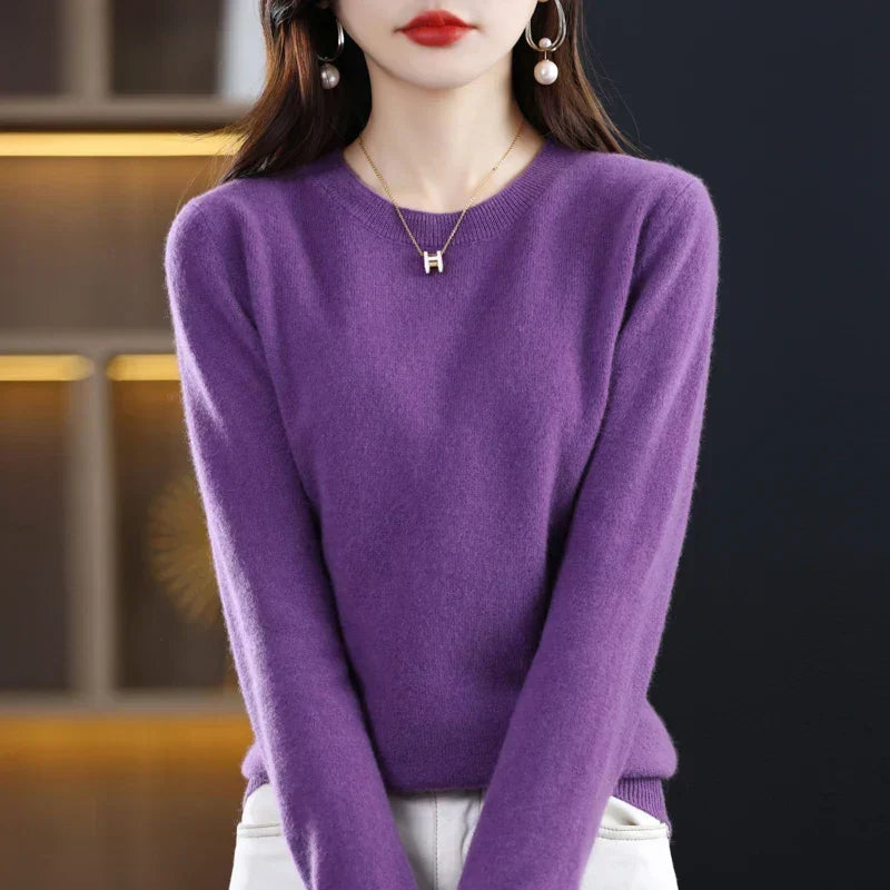 Model wearing the jumper in rich purple with white trousers, arms relaxed at her sides 12