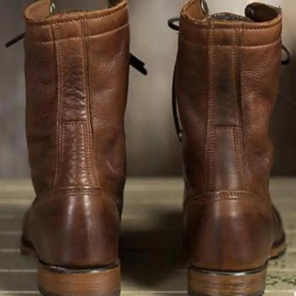 Back view of two brown leather boots showing the vertical heel stitching, stacked heels and loosely trailing laces. 2