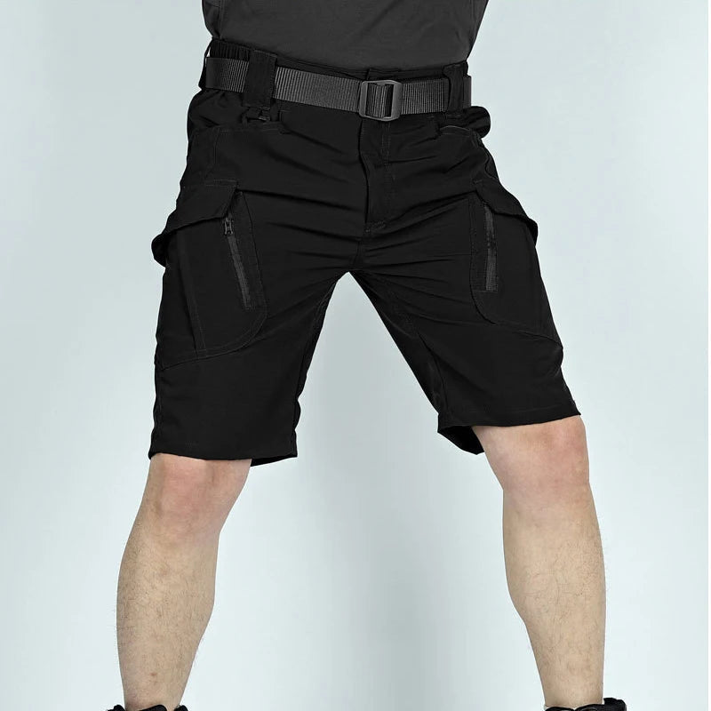 Man wearing black cargo shorts with a belt, seen from the front, showing both zipped thigh pockets and the knee-length cut. 6