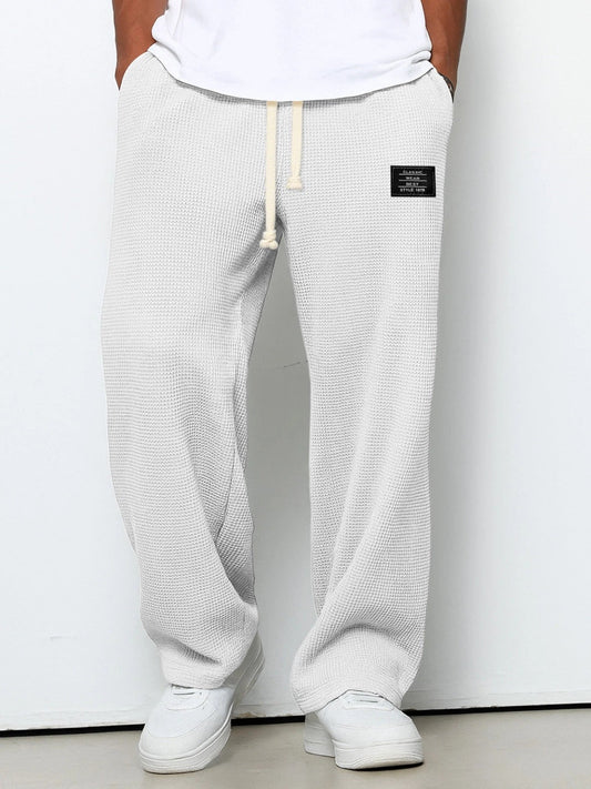 Model wearing the waffle knit wide leg trousers in off-white, hands in pockets, with white trainers 2