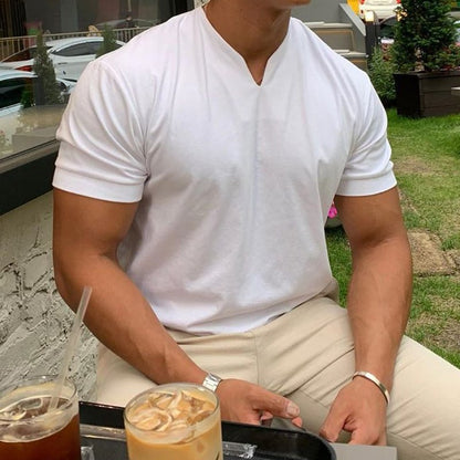 White V-neck tee worn with beige trousers by a seated model at an outdoor table with iced drinks. 4