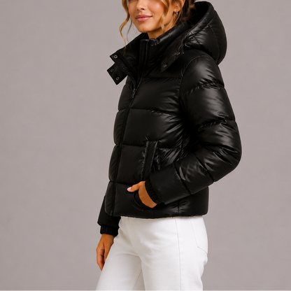 Side view of a model in the black glossy puffer jacket with hood up, hand in pocket 3