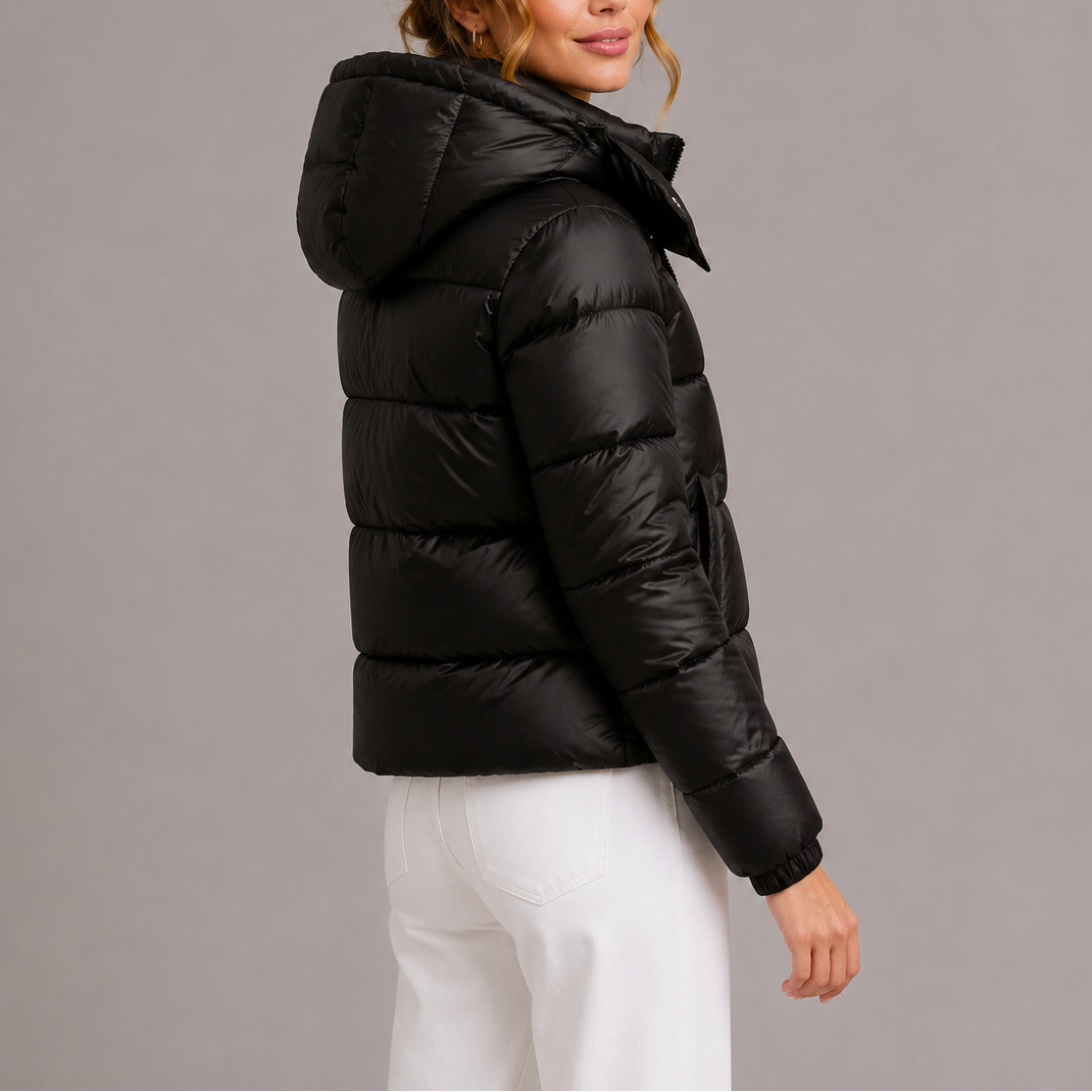 Rear three-quarter view of a model in the black quilted jacket with its hood raised 4