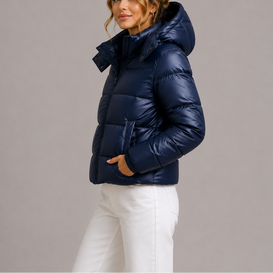 Side view of a model in the navy glossy puffer jacket, hood up, hand in pocket 1