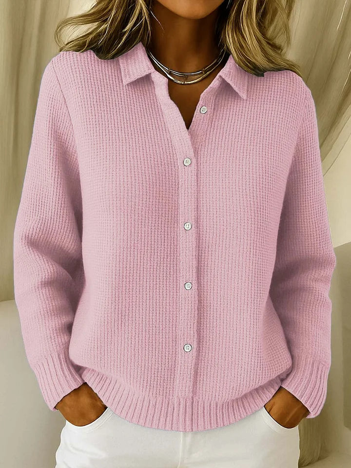 The same buttoned collared jumper in soft pink, worn by a model with a silver necklace and white trousers. 2