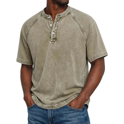 Man in a washed khaki-beige short-sleeve Henley with raglan sleeves and three-button placket, hands in jeans pockets. 9