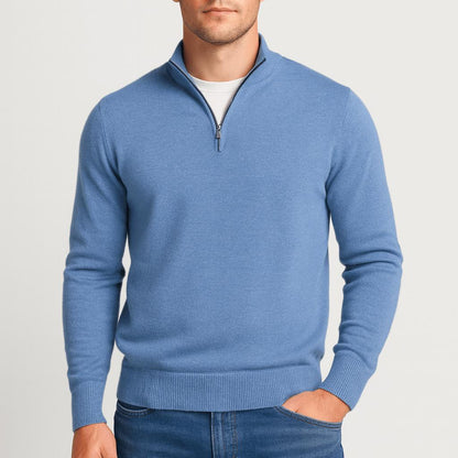 Man wearing a blue quarter-zip knit jumper, one hand in the pocket of his blue jeans, front view. 13