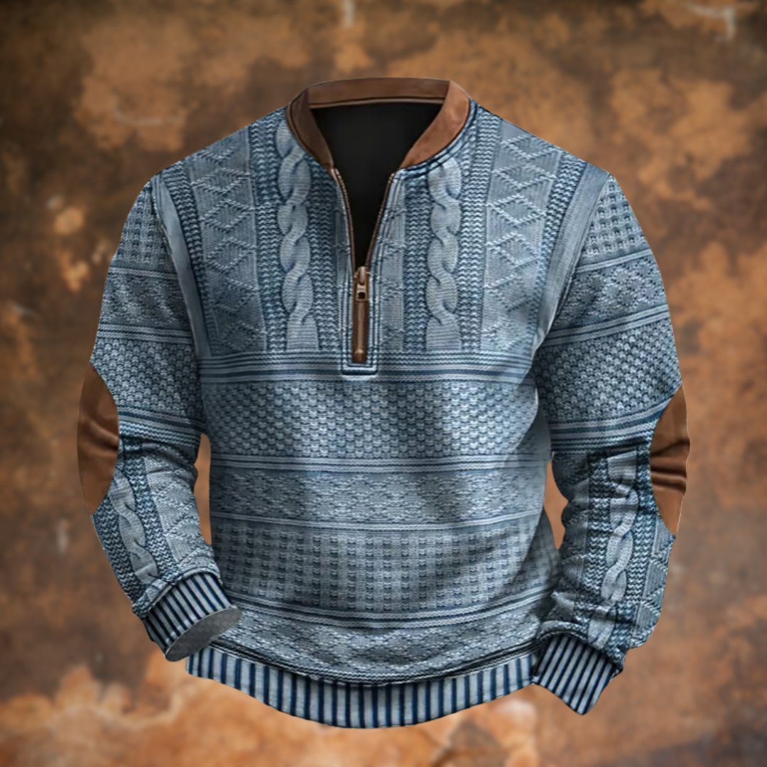 Front view of the quarter-zip jumper in blue-grey, with cable and diamond knit patterns, brown collar and elbow patches, striped cuffs. 1